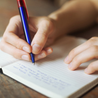 a person's hands writing in a diary