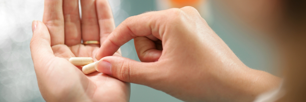 Medications That Can Be Dangerous in Summer Close up view of young woman holding ginseng vitamins and minerals pills in hand with capsule bottle on table. High angle view