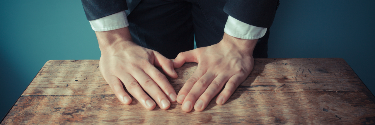 When the Doctor's Office Feels Like a Principal's Office A man resting his hands on a table, standing over it.