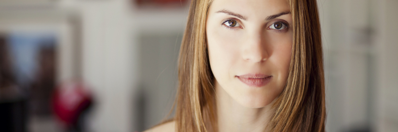 Don't Tell People With Chronic Illness That They Don't 'Look' Sick woman with a red shirt and blonde hair looking at the camera