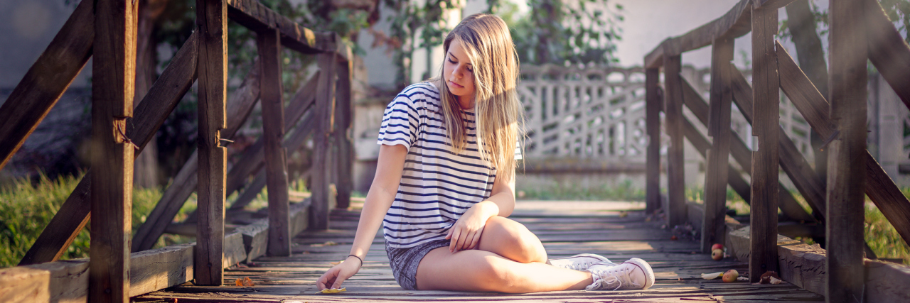 To My 14-Year-Old Self Diagnosed With Crohn's Disease A picture of a young woman sitting on a bridge.