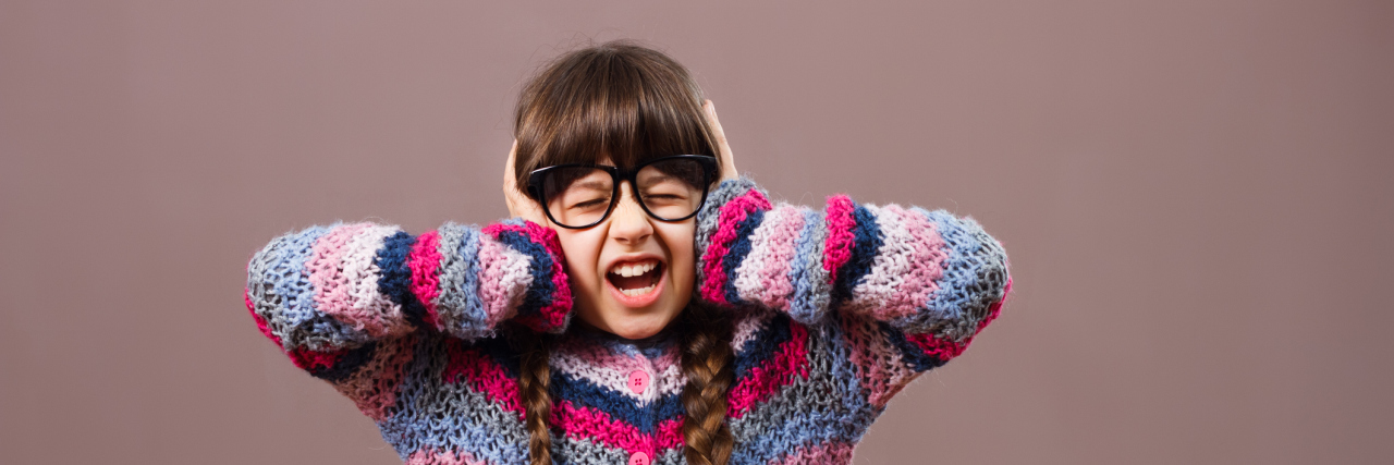 Girl feeling overwhelmed covering her ears and closing eyes shut and screaming