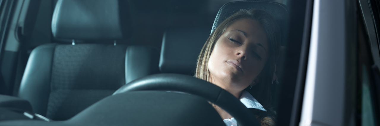 A picture of a woman sleeping in her car.