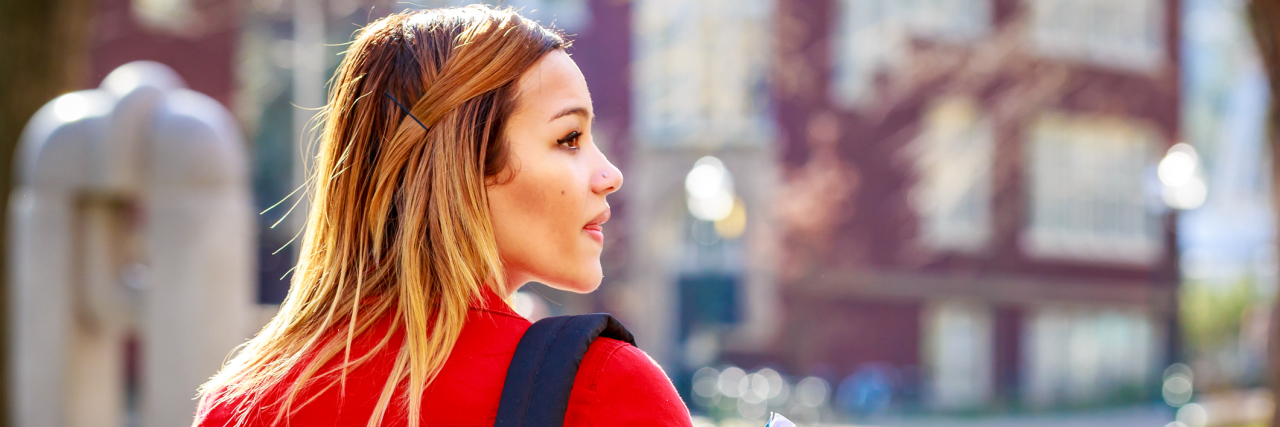 5 Things to Know Before You Go to College With a Chronic Illness A young student holding books and a backpack, walking to an academic building.