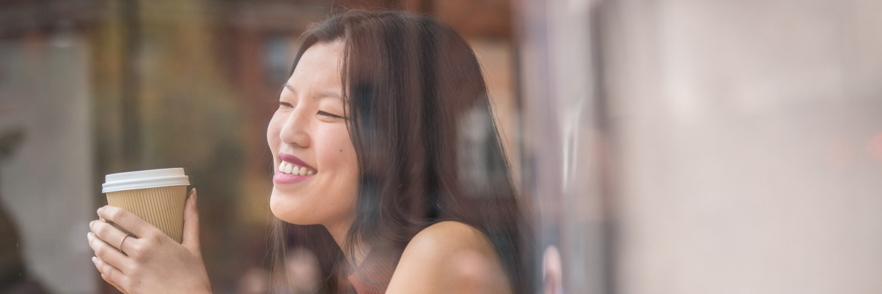 Learning the Difference Between My Mental Illness and Myself young chinese woman sitting next to windows in cafe.