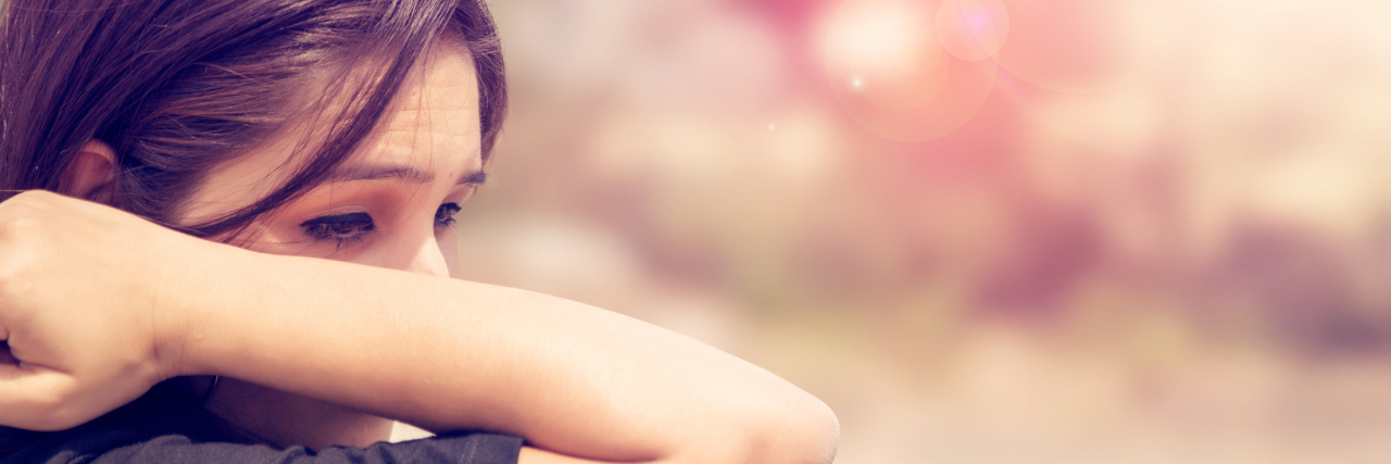 It's OK to Cry Over a Donut When the Ease of Eating Is Gone A woman standing outside, wiping away her tears with her arm.