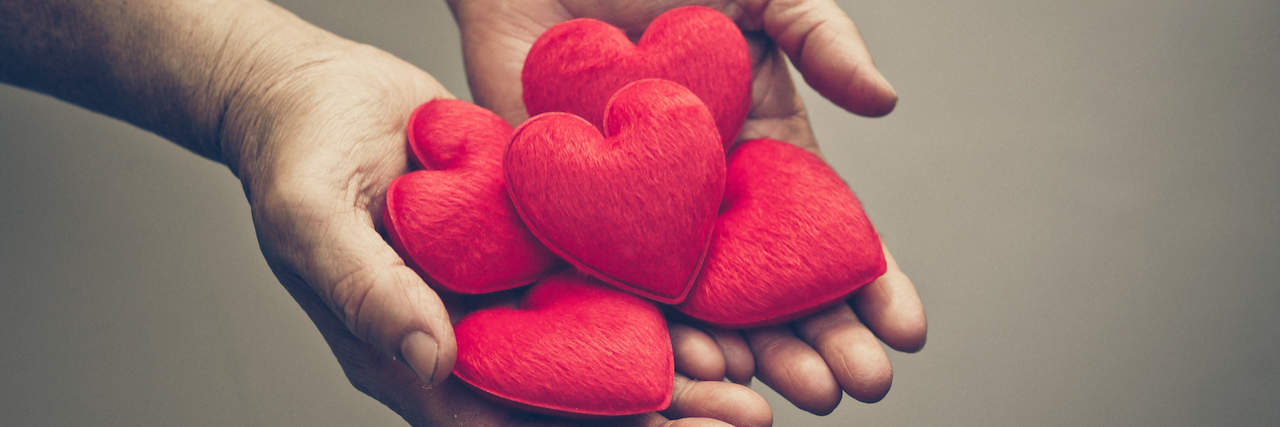 What Is Compassion Fatigue? A pair of handing holding hearts