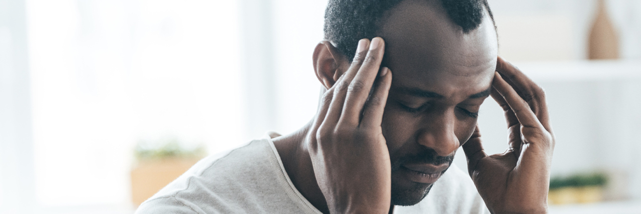 A picture of a man with his hands to his head, looking tired.