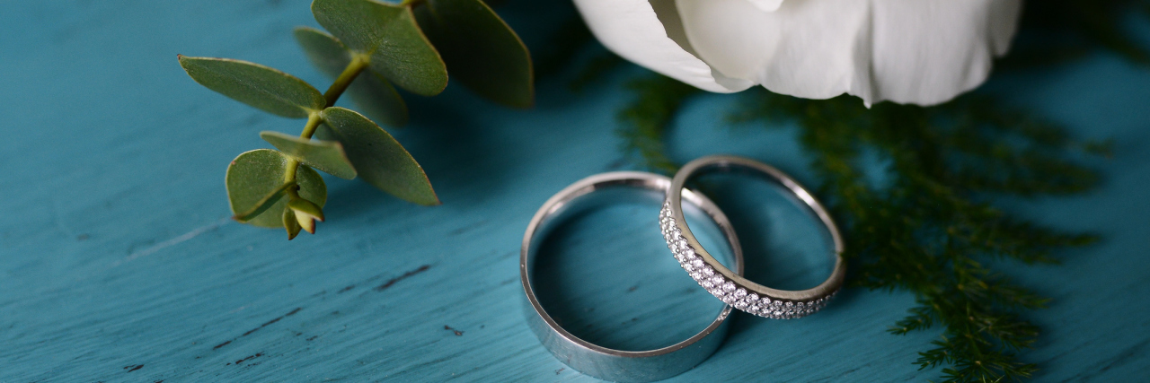 Thank You to My Husband for Supporting and Loving Me Through Illness wedding rings on turquoise table