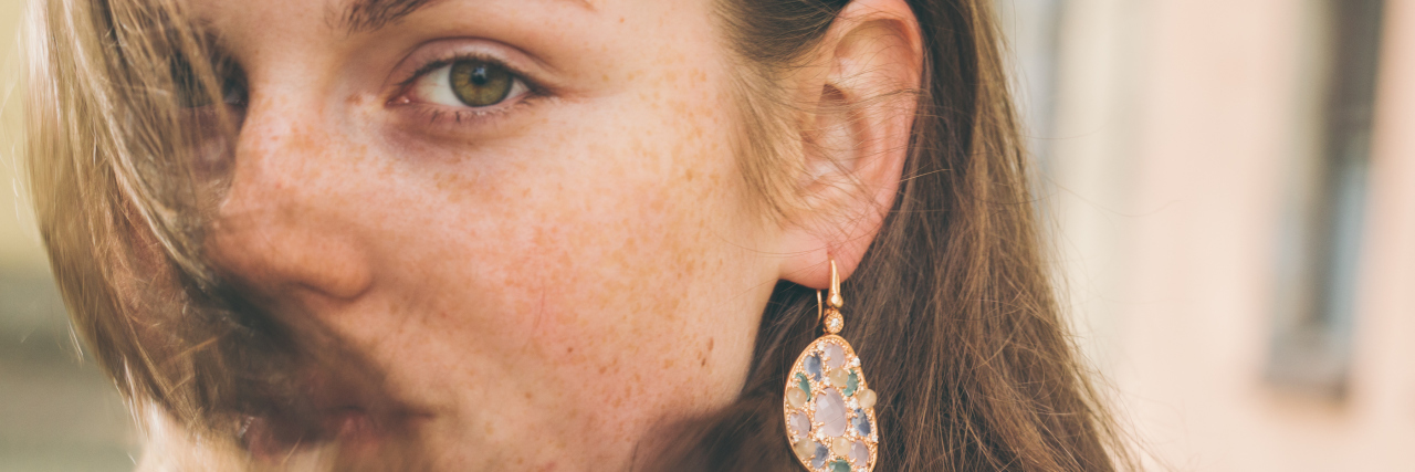 The Problem With Making Illnesses the Butt of a Joke A woman, with her head turned and hair in her face, looking at the camera.