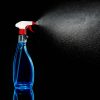 A spray bottle spraying in front of a black background.
