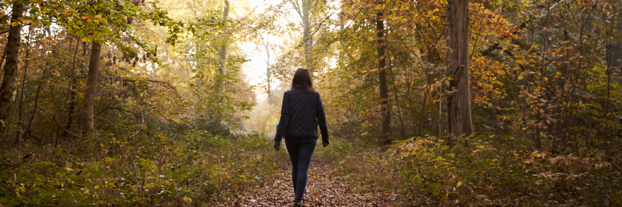 What It's Like to Be a 'Medical Trailblazer' Woman Walking Along Path In Autumn Woodland