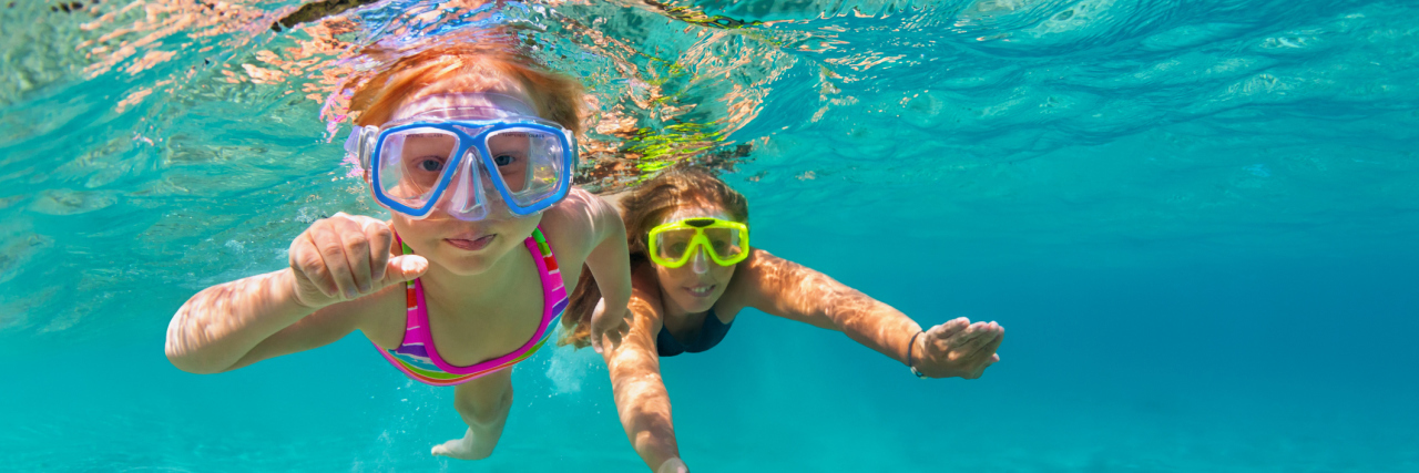 Letter to the Mom of Typical Kids I Met at the Gym Two girls swim underwater with goggles looking at camera