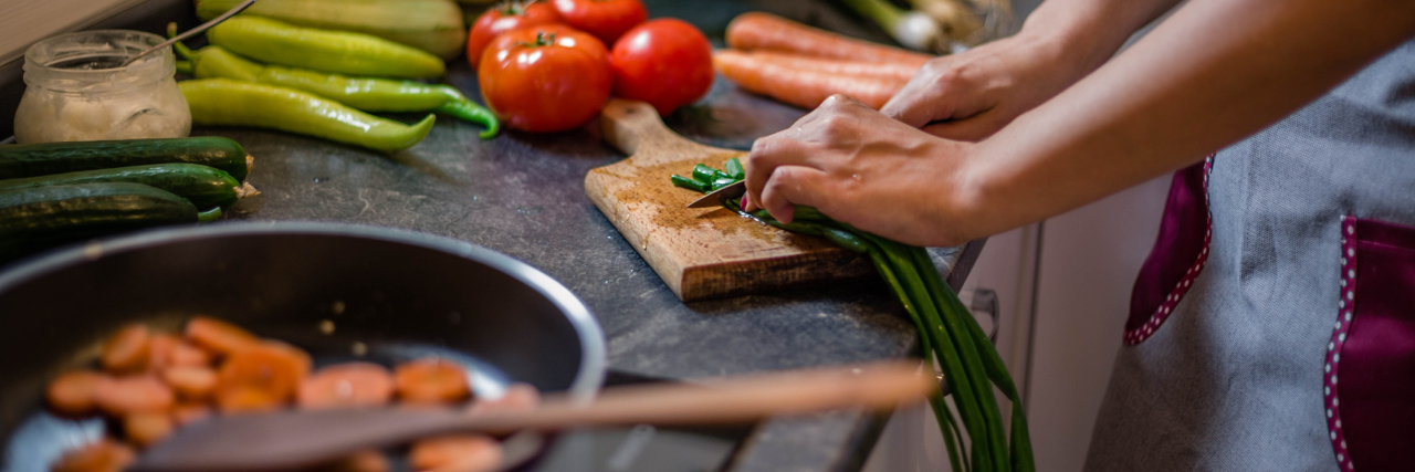 A woman cutting vegetables and cooking.