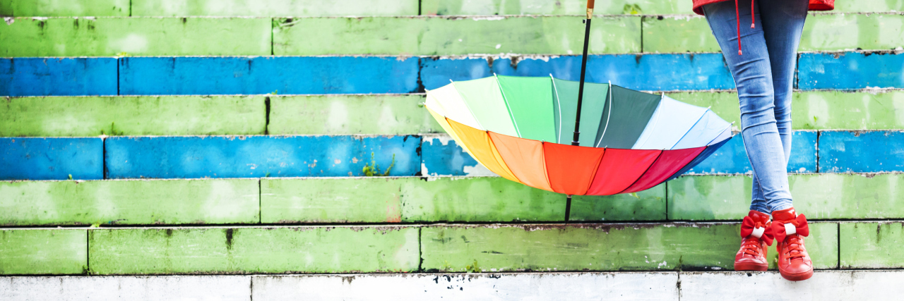 Chronic Fatigue Syndrome Isn't All Doom and Gloom A picture of a person's bright rain boots and umbrella, as she stands on brightly colored steps.