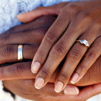 Hands of married couple wearing wedding rings.