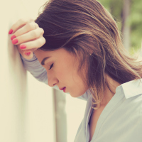 A woman leaning against the wall, looking upset.
