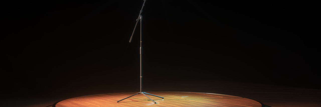 Teaching Improvisation to People With Down Syndrome A dark stage with a microphone