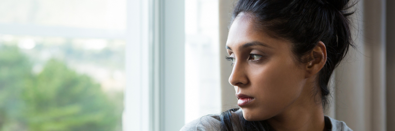How a Skiing Accident Has Affected My Mental and Physical Health A young woman looking out her window, looking as though she's reflecting.