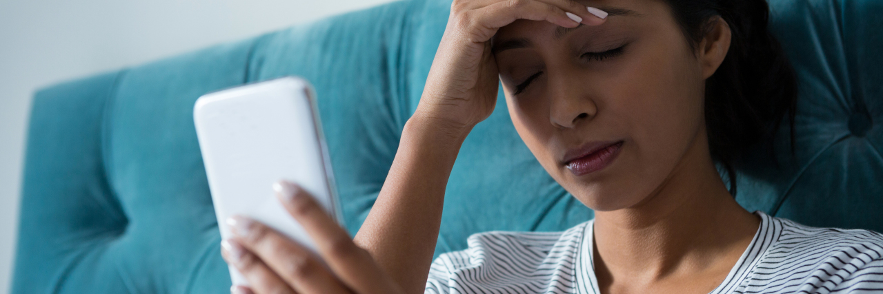 What to Remember If You Are Facing Illness and Comparing to Peers Sad young woman holding mobile phone in bedroom at home