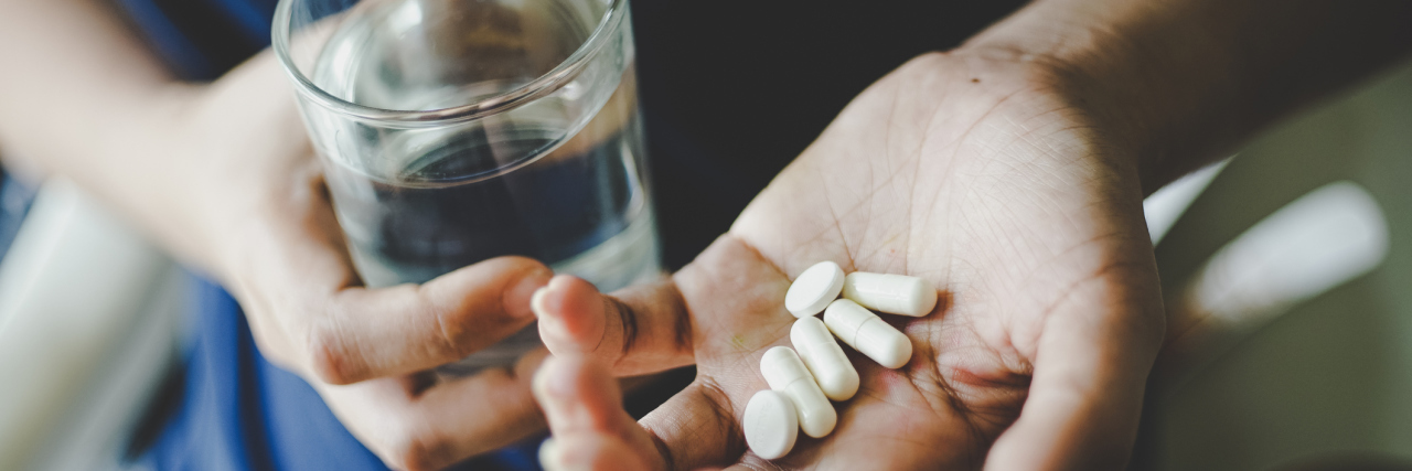 8 Surprising Foods That Can Be Dangerous to Eat With Medication hands holding pills and glass of water