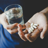 hands holding pills and glass of water