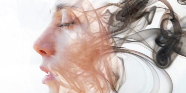 double exposure portrait of a woman with her eyes closed, and the photo fades into wisps