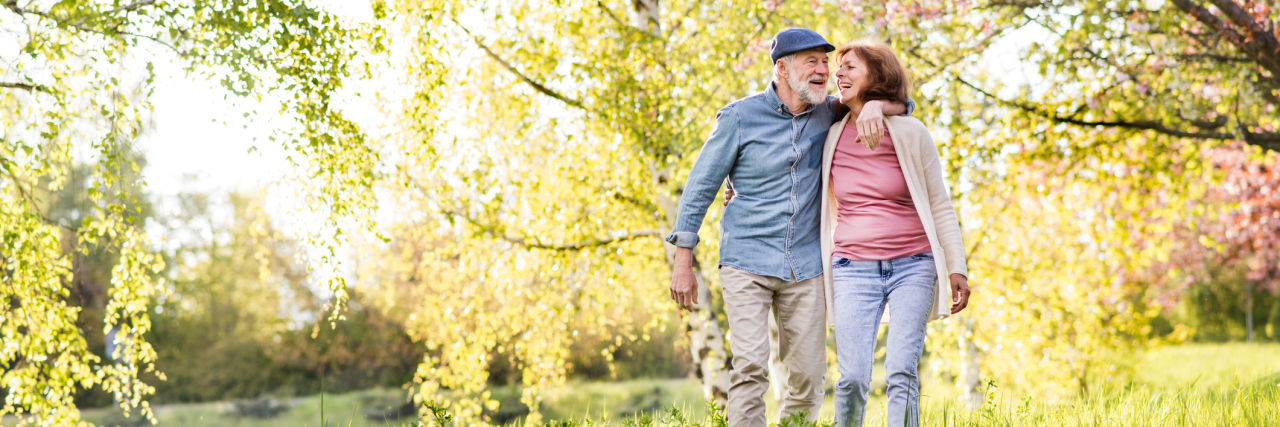 5 Ways You Can Support Your Partner Living With Chronic Illness A picture of a couple walking in a park.