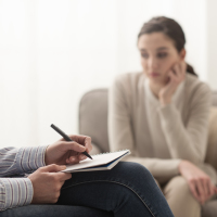 A psychologist is taking notes on a writing pad while her patient is in session.