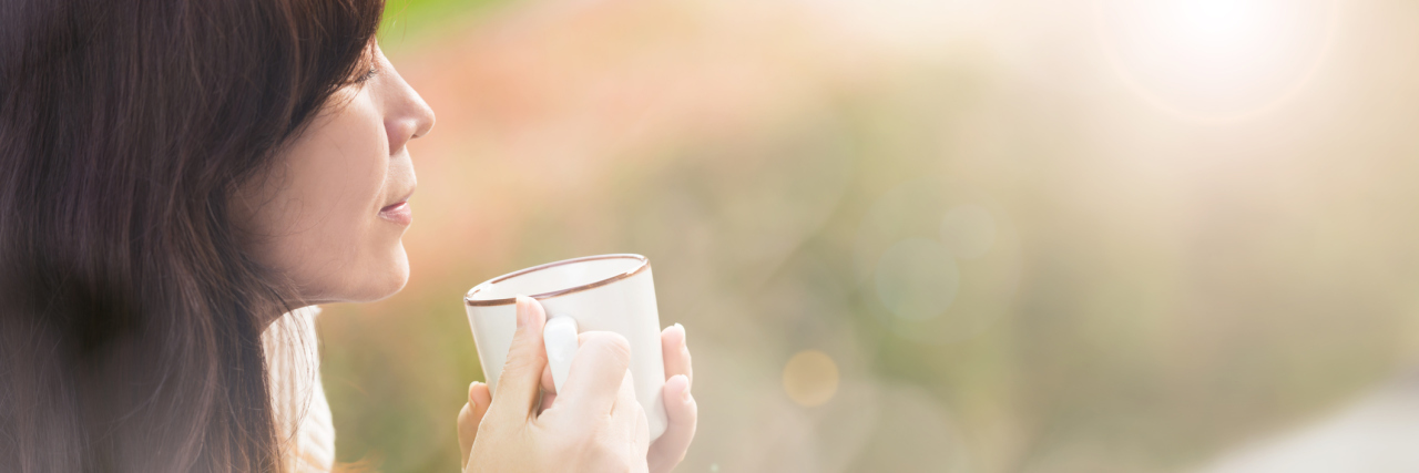 How I Plan to Kick Ass After a Restless Night With POTS A picture of a woman outside, drinking coffee.
