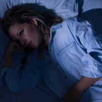 A woman laying awake in a dark room.