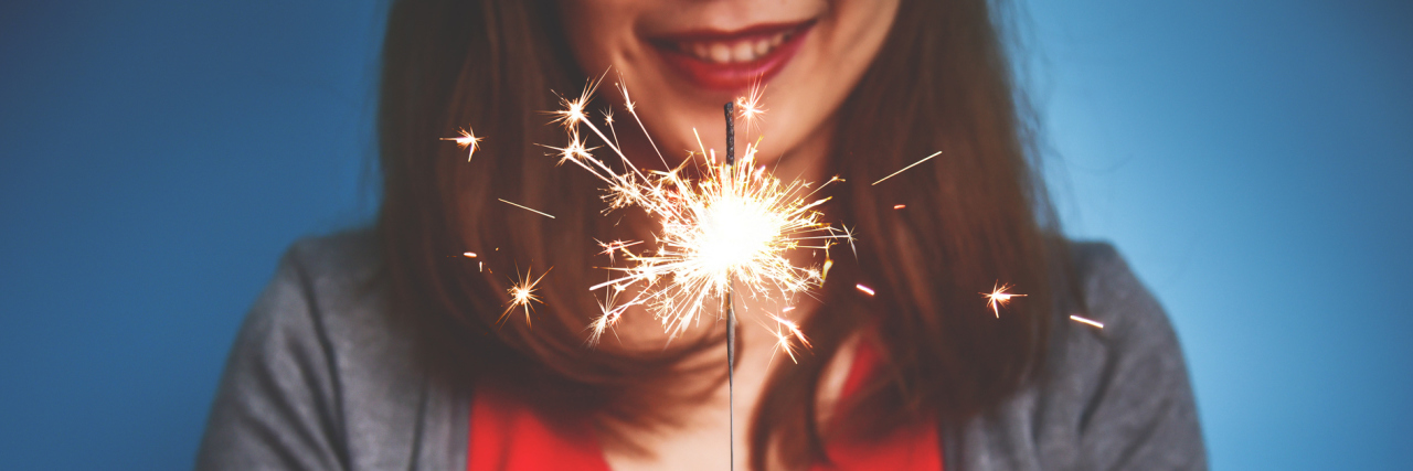 The Goals I've Set That Have Added Light in the Midst of Illness A picture of a woman holding a sparkler.