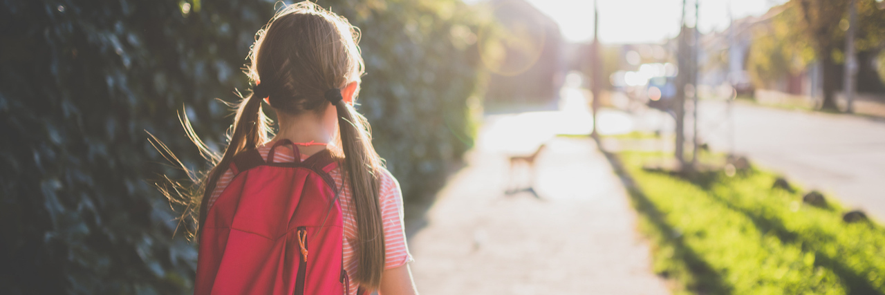 Girls wearing red backpack walking to school