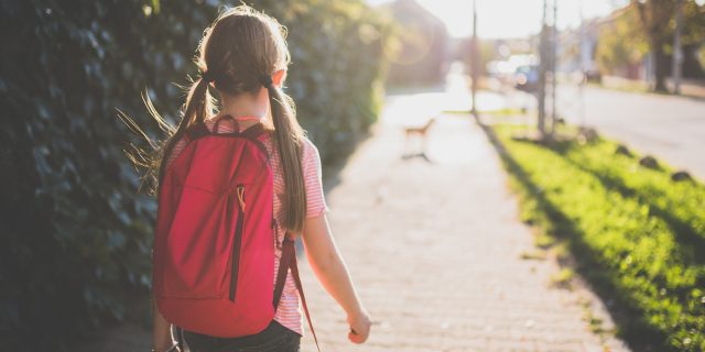 Girls wearing red backpack walking to school