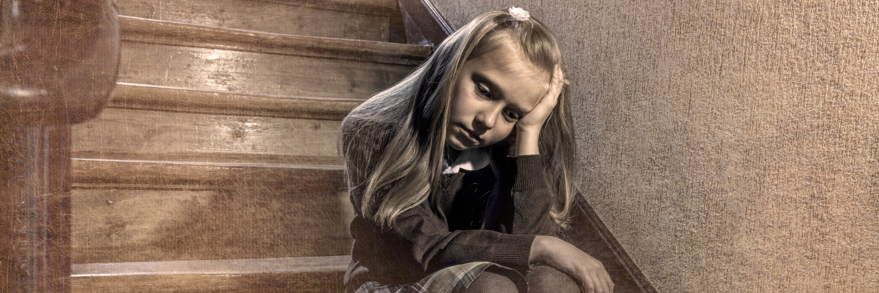 Depressed and worried schoolgirl sitting on staircase.