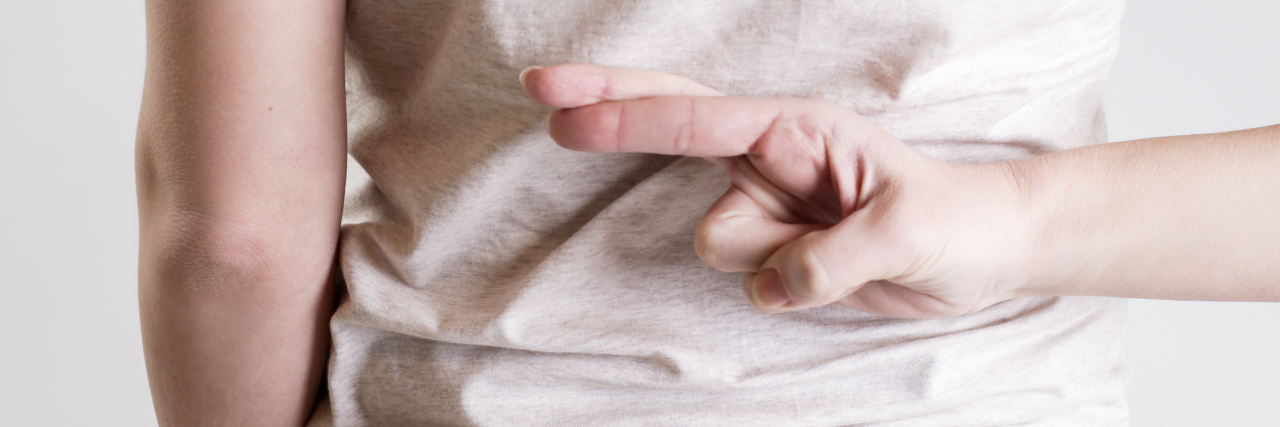 10 Lies I Tell Myself About My Chronic Fatigue A woman crossing her fingers behind her back.