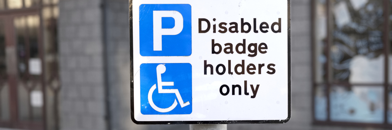 Disabled parking space sign post for badge holders only at shopping mall