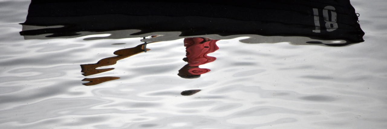 A blurred reflection of a man in a boat with a paddle.
