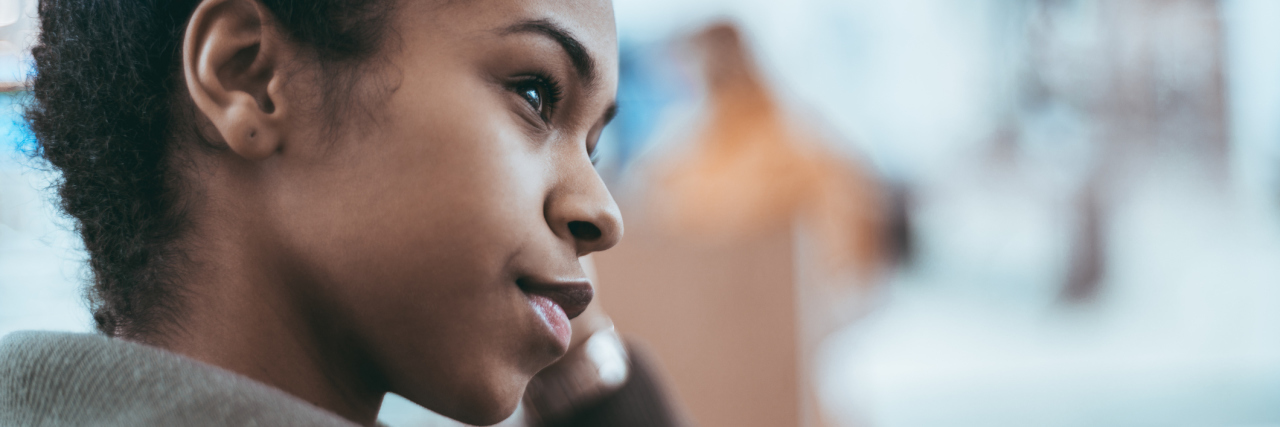 To Women Who Think Race Doesn't Affect Chronic Illness Close-up side view of a girl with a curly hair and in a dark-green light overcoat, looking aside; with defocused background