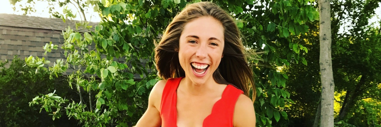 Why I Get Excited When You Say You Know Someone With IBD A picture of the woman smiling as she stands outside in a red dress.