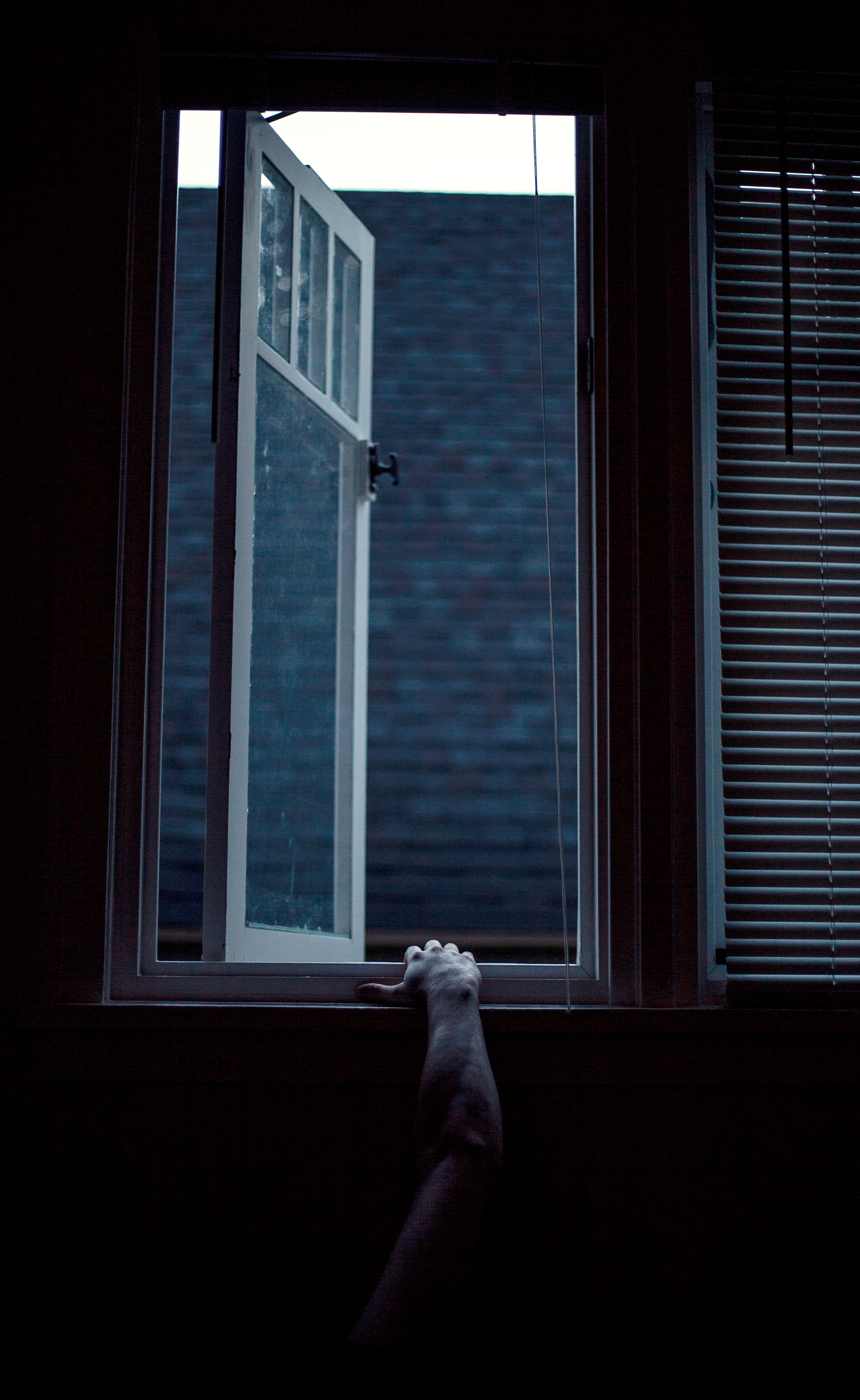 man's hand reaching up to clutch window ledge from darkness below - photo by Laurence Boswell of Only Human Photography