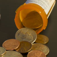 A pill bottle on its side, with money spilling out of it.