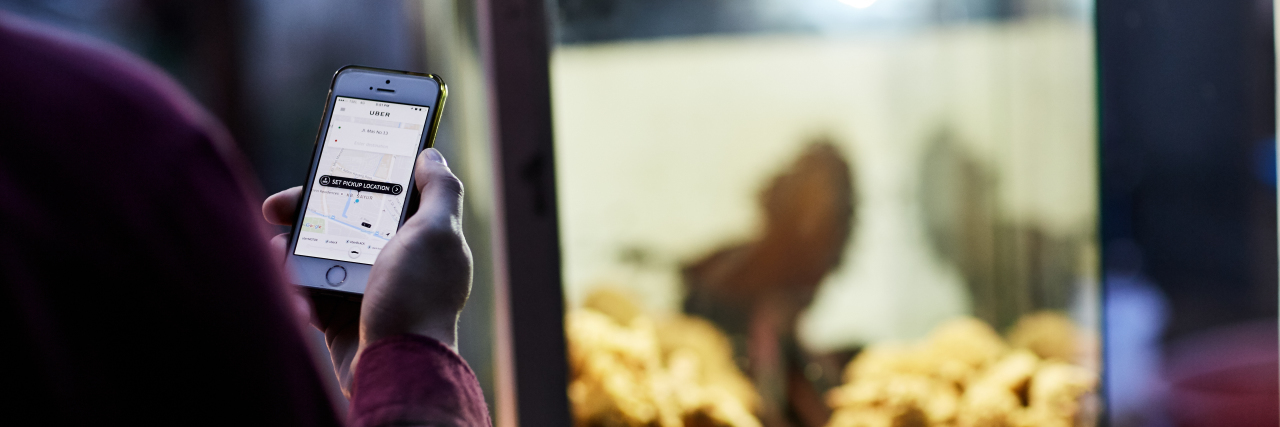 9 Things Uber and Lyft Drivers Should Know About Disabled Passengers man holding phone wiith uber app open