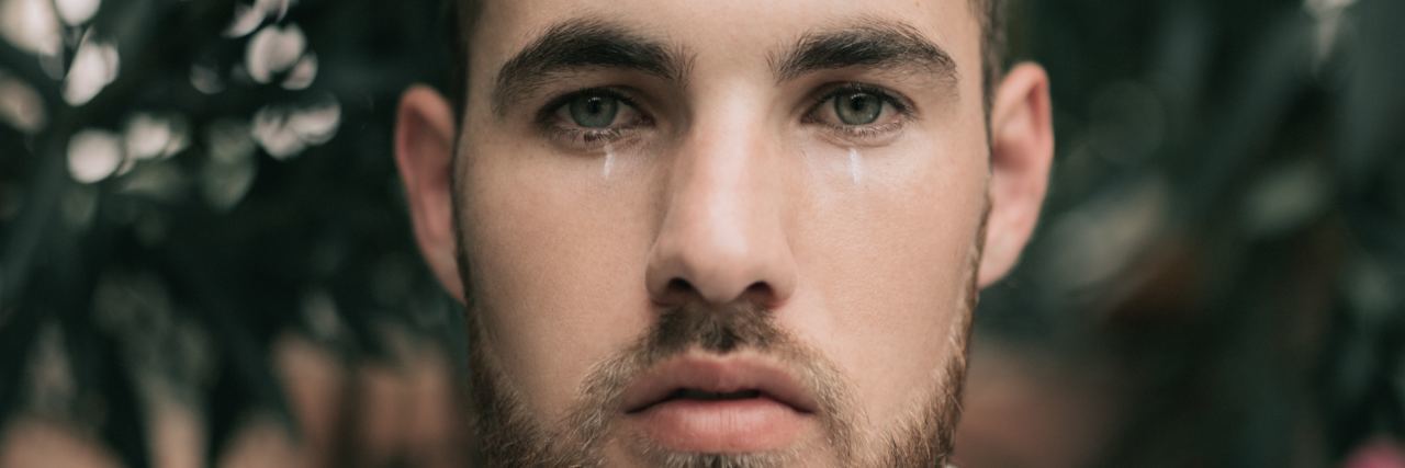 Fatherhood, Mental Health and the Cycle of Toxic Masculinity man standing in front of flowers looking into camera and crying