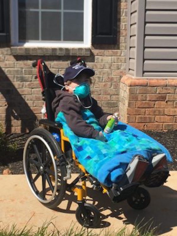 the author's son in a wheelchair, wearing a mask