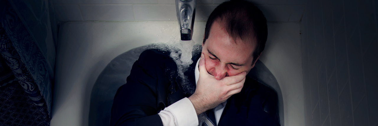 Photos That Show Different Parts of Bipolar Disorder man lying in bathtub with hand covering eyes fully clothed - photo by Laurence Boswell of Only Human Photography