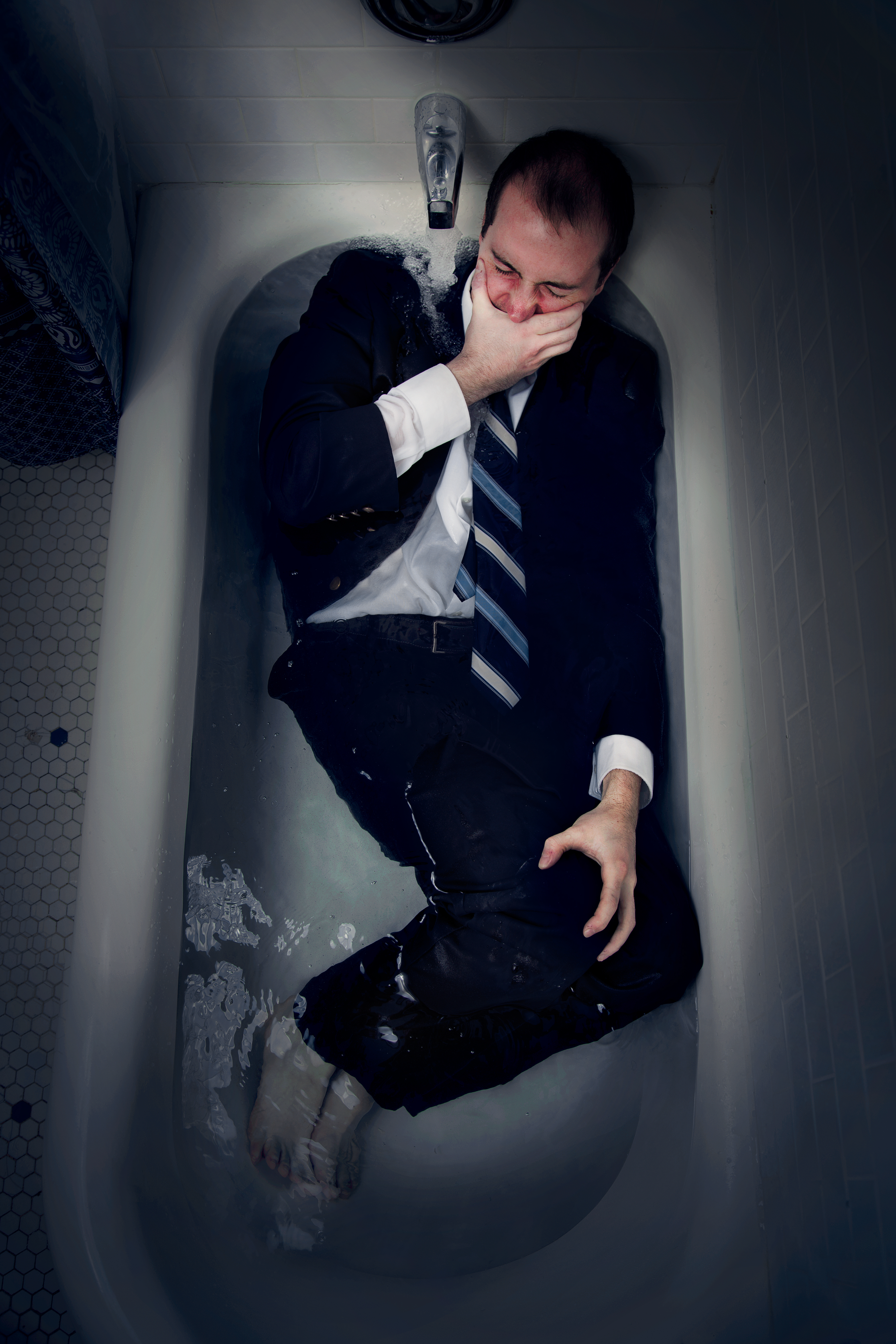 man lying in bathtub with hand covering eyes fully clothed - photo by Laurence Boswell of Only Human Photography