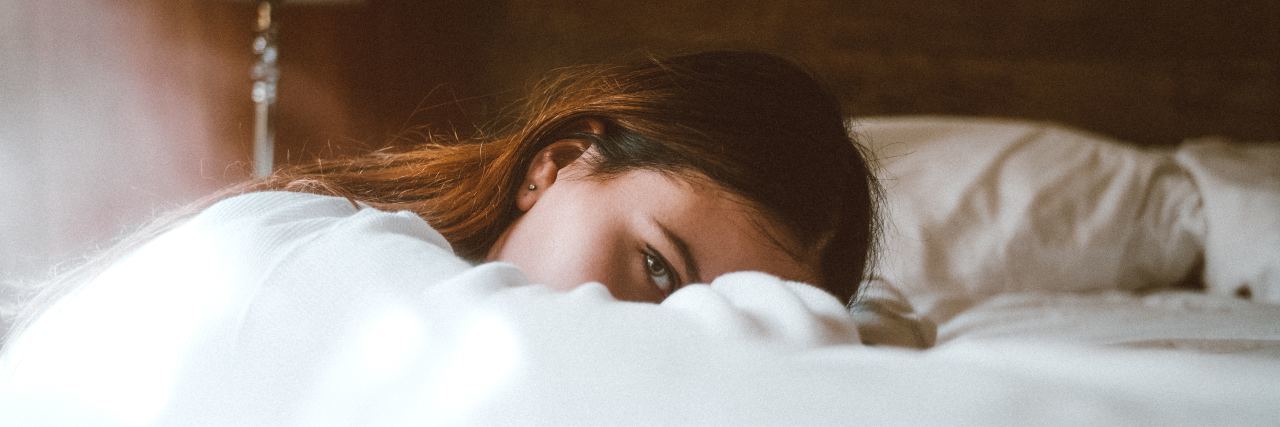 woman leaning on bed looking at camera tired