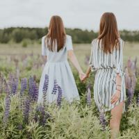 two women holding hands in field of flowers