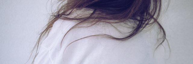 close up of girl with long hair holding her side from behind